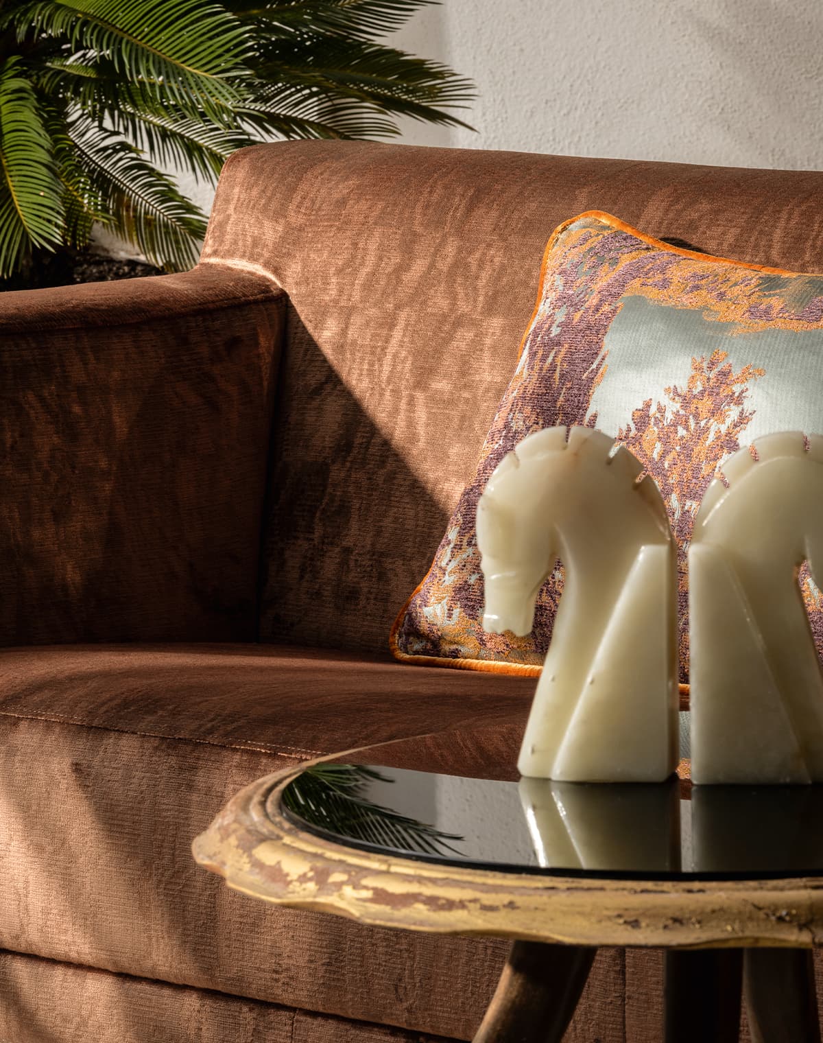 Sofa mit Rostbraunem Bezugstoff und ein Kissen mit abstraktem Printmuster.