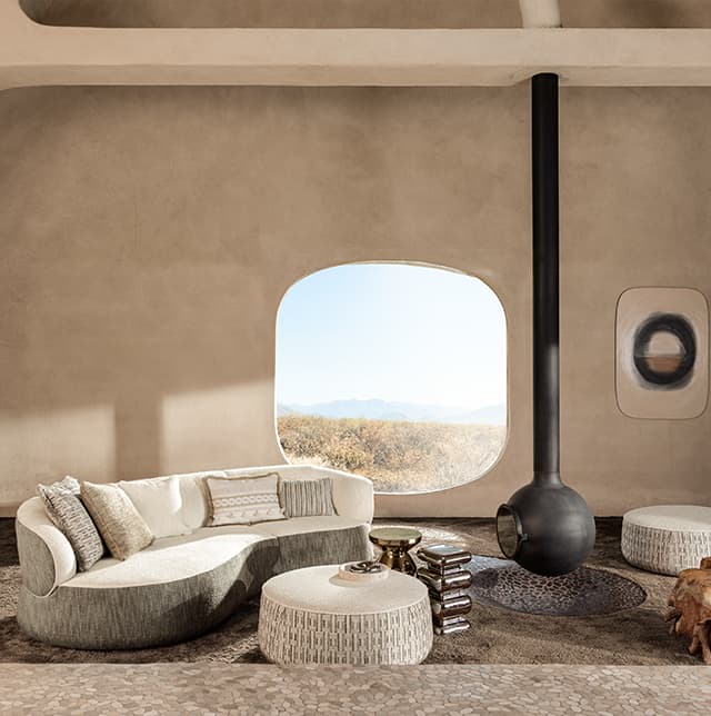 Graues Sofa mit grauen Kissen und zwei graue Poufs.