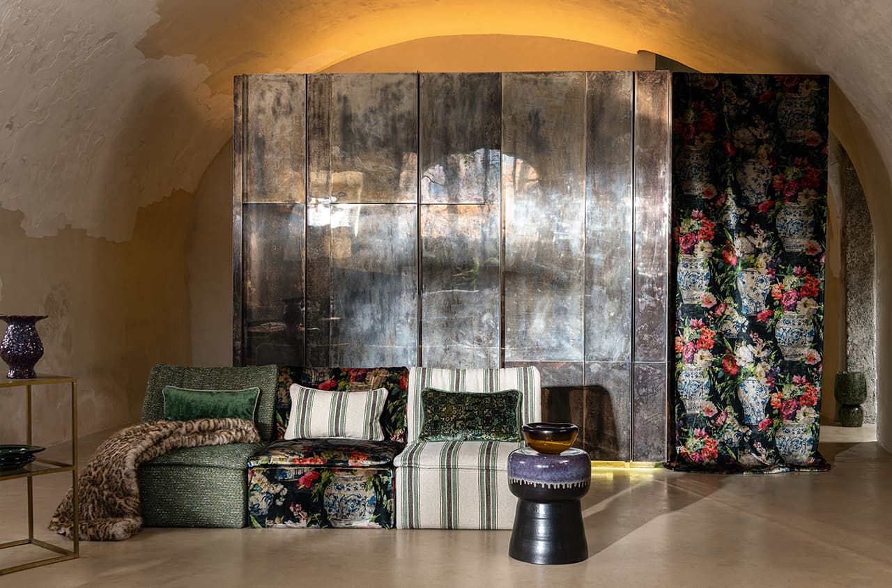 Verschieden gemusterte Sofaelement und ein Vorhang mit floralem Muster.