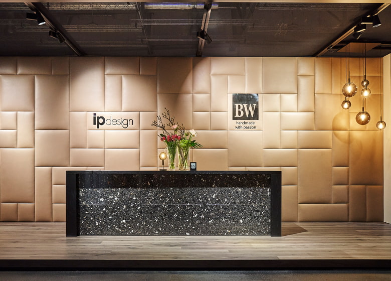Messtandfoto mit Empfangstresen. An der Wand im Hintergrund sind die Logos von BW Bielefelder Werkstätten und ipdesign zu sehen.