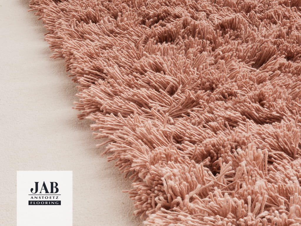 Nude- pinkfarbener Teppich mit einem Kontrast zwischen dichter Grundfläche und voluminös getufteter Form