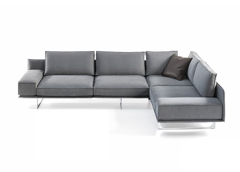 Freisteller eines grauen Sofas hohen Kufen und einem schwarzen Deko-Kissen.