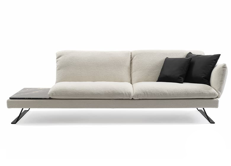 Freisteller eines weißen SOfas mit Anbautisch. Es besteht aus zwei Sitzflächen. Auf dem Sofa liegen zwei schwarze Deko-Kissen.