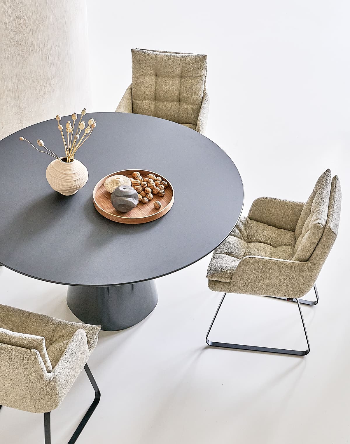 Tisch Roxy in schwarz auf einem weißen Boden, an dem Tisch stehen beige Stühle