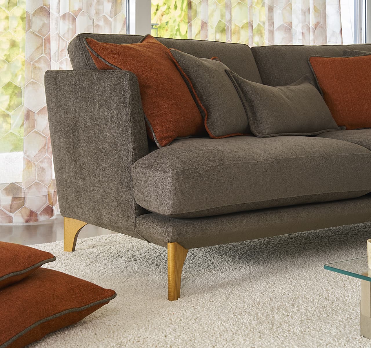 nahaufnahme eines braunes Sofas mit orangenen Kissen