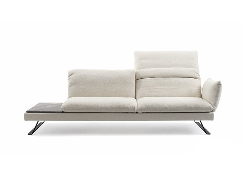 Freisteller eines weißen Sofas mit ausgeklappter Rückenlehne und einem angebauten Tisch.