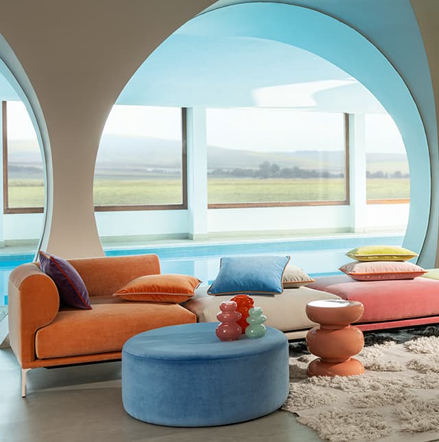 Sofaelemente und Kissen in bunten Velvet-Bezugsstoffen.