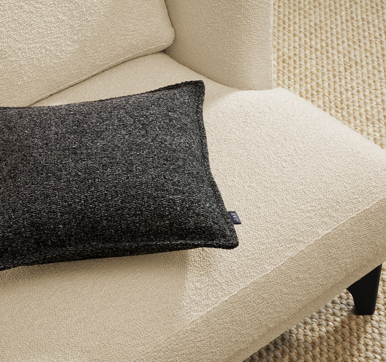 Detailaufnahme von dem Sessel Polo Living in weiß mit einem grauen Kissen