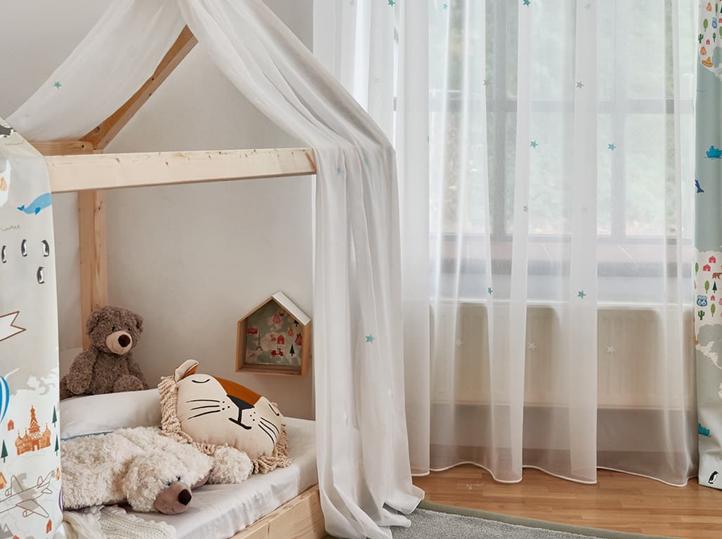 Weiße transparente Gardine bedruckt mit Sternen im Kinderzimmer