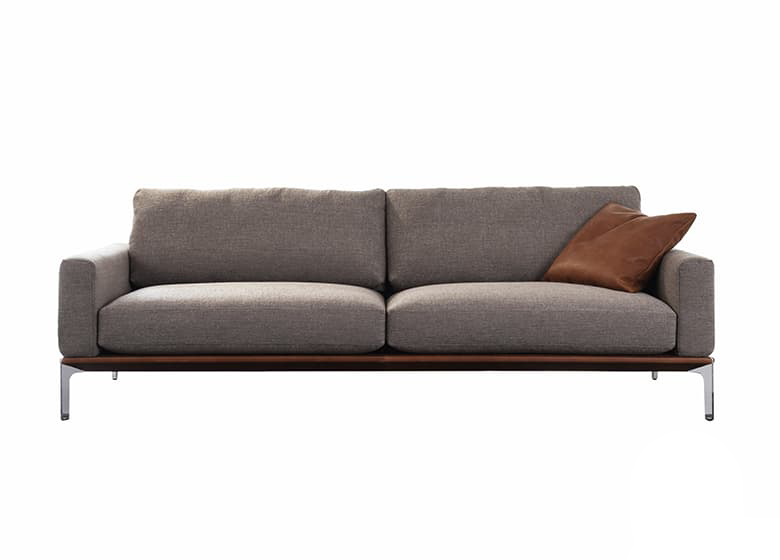 Freisteller eines braunen Sofs mit einem Deko-Kissen. Das Sofa besteht aus zwei Sitzflächen.