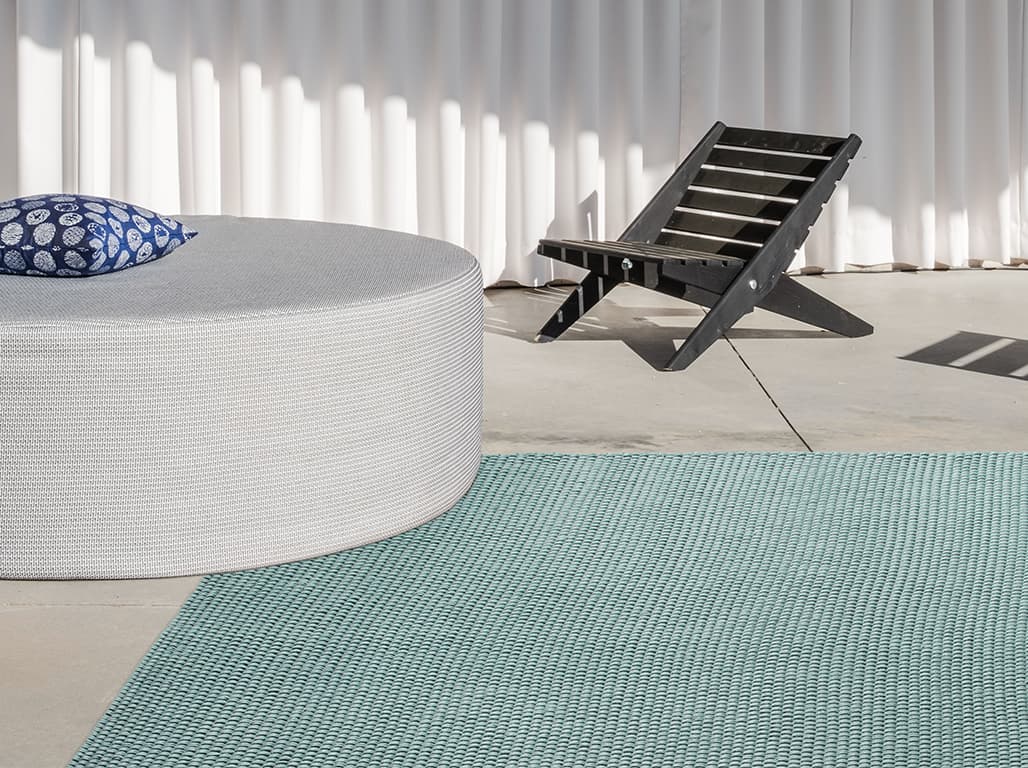 Grüner Outdoor-Teppich auf der Terrasse mit runden grauen Hocker und braunen Holz Liegestuhl